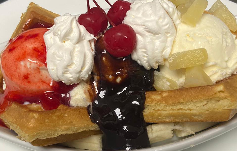 waffle with cream accompanied with cherry and chocolate sauce